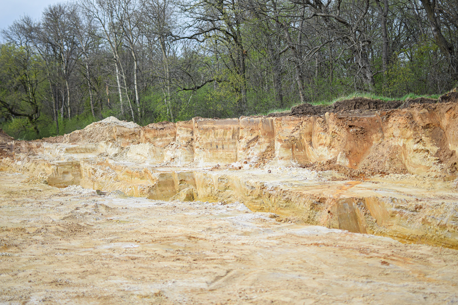 The home’s footprint emerging as a stepped earthwork tiered into the bluff slope.
