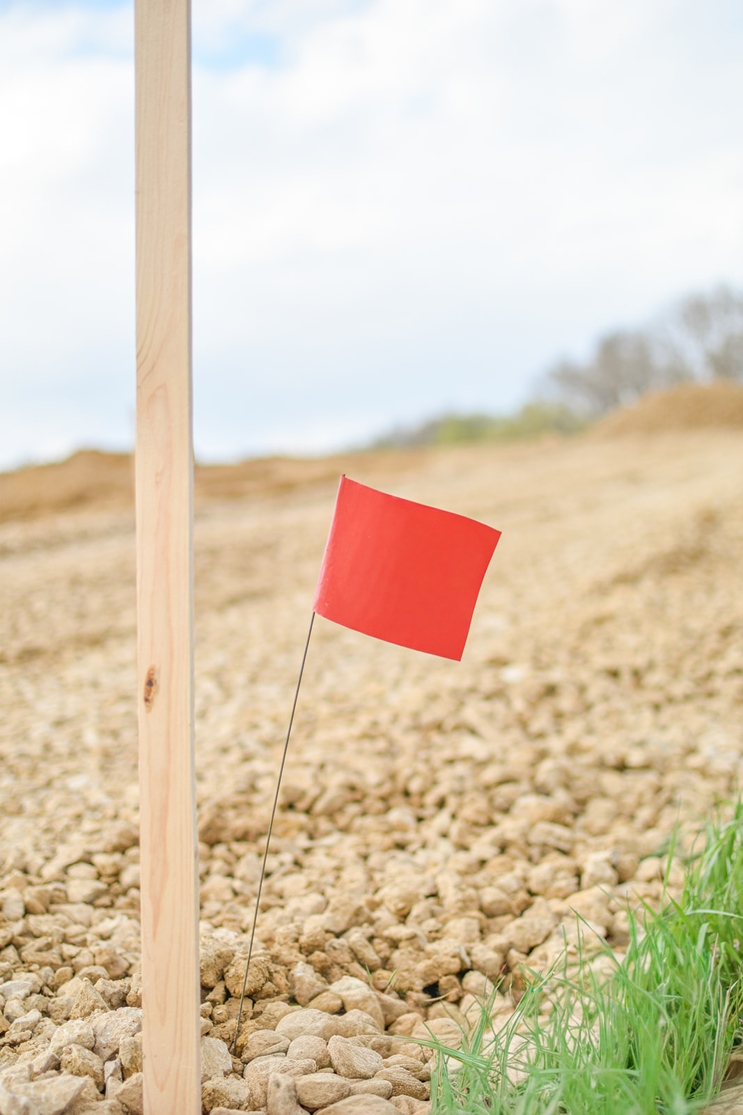 A wooden stake and red surveyor flag marking the corner of the foundation layout.