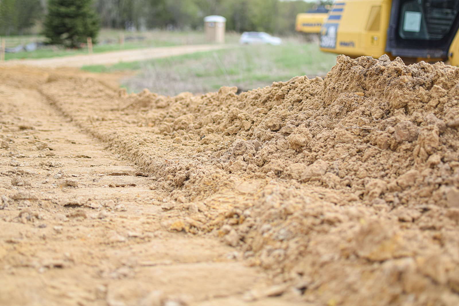 Excavator tracks pressed into fresh subsoil along the new access cut.