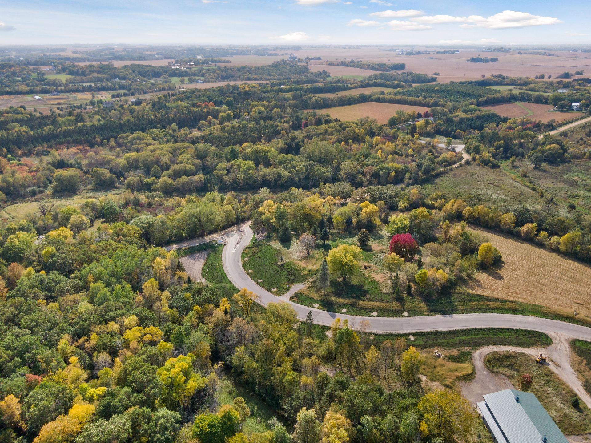 Wide aerial view of the Oakridge property and surrounding farmland, with the access road threading through the autumn tree line.